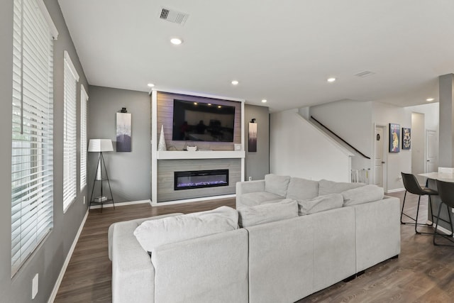 living room with a wealth of natural light, visible vents, and wood finished floors