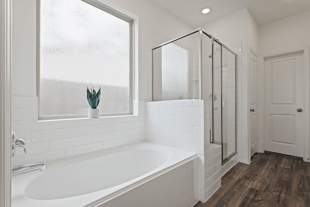 full bath featuring a garden tub, a shower stall, and wood finished floors