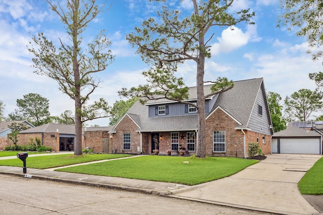 view of front of home with a front lawn, a shingled roof, brick siding, and an outbuilding