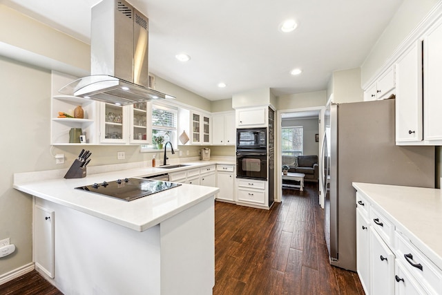 kitchen featuring island range hood, black appliances, a sink, a peninsula, and dark wood-type flooring