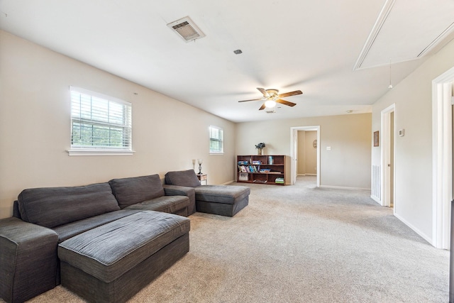 living room with attic access, ceiling fan, visible vents, baseboards, and light colored carpet