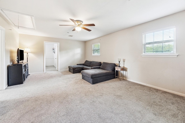 carpeted living room with attic access, ceiling fan, and baseboards