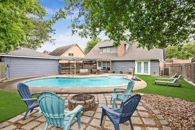 view of swimming pool featuring an outdoor fire pit, a fenced backyard, a yard, a fenced in pool, and french doors
