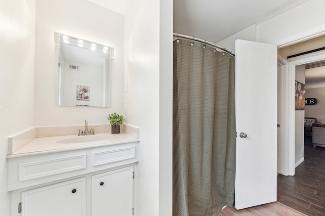 bathroom with wood finished floors, visible vents, vanity, and curtained shower