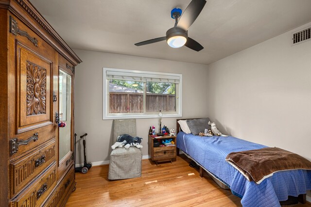 bedroom with baseboards, a ceiling fan, visible vents, and light wood-style floors