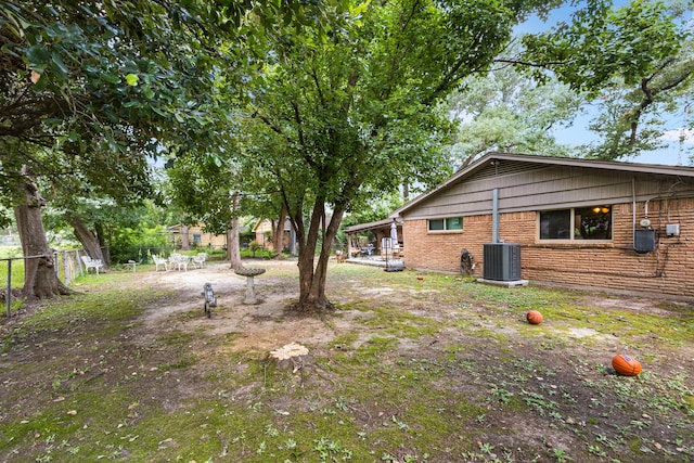 view of yard featuring central AC and fence