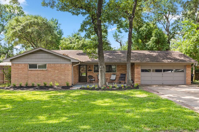 ranch-style home featuring concrete driveway, a front lawn, covered porch, a garage, and brick siding