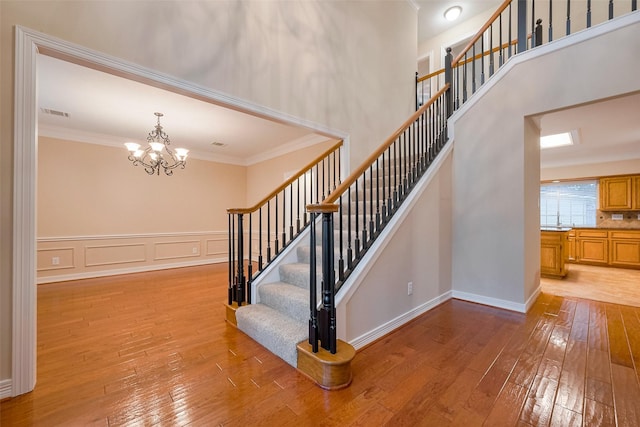 1842 Lake Winds, Missouri City, TX 77459 - stairs with crown molding, a decorative wall, a chandelier, and hardwood / wood-style flooring
