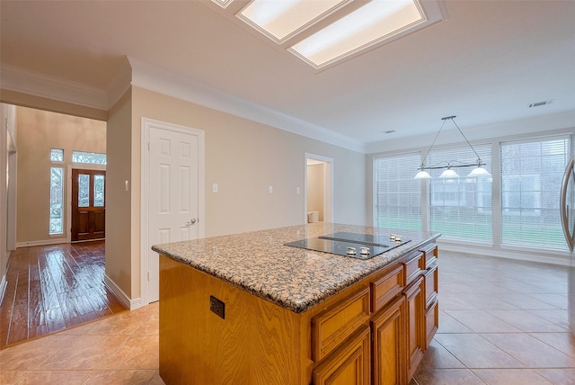 1842 Lake Winds, Missouri City, TX 77459 - kitchen with a center island, brown cabinets, light stone countertops, black electric stovetop, and ornamental molding