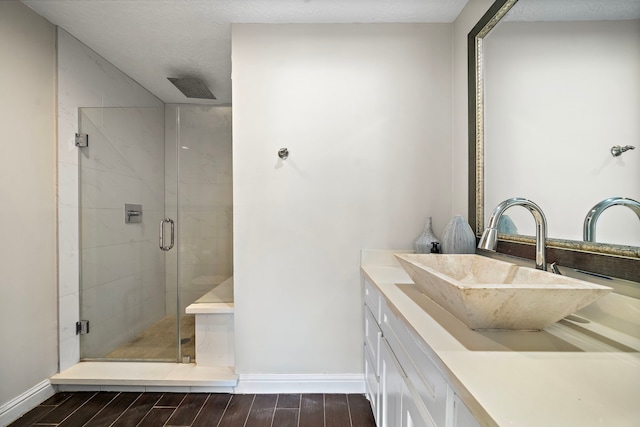 bathroom featuring wood finished floors, baseboards, vanity, and a stall shower