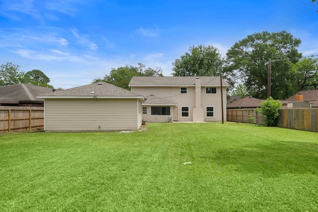 rear view of property featuring a lawn and a fenced backyard