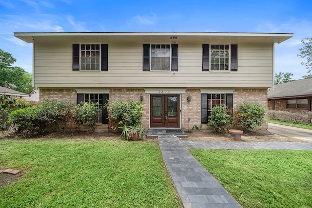 colonial inspired home featuring a front lawn, french doors, and brick siding
