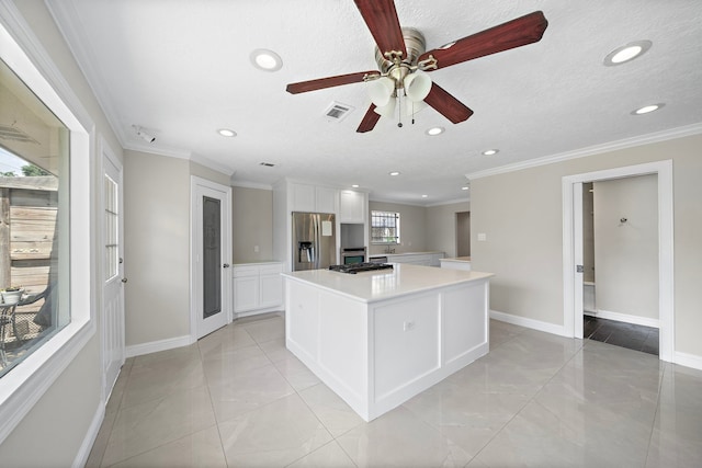 kitchen featuring white cabinets, stainless steel fridge, visible vents, a ceiling fan, and a kitchen island