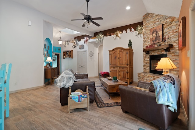 25672 Magnolia Pines Dr, Magnolia, TX 77355 - living area featuring arched walkways, ceiling fan, a stone fireplace, light wood-style flooring, and baseboards