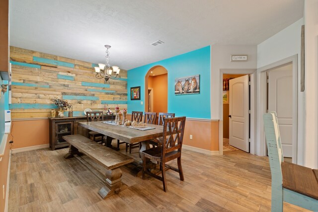 25672 Magnolia Pines Dr, Magnolia, TX 77355 - dining space with wooden walls, a chandelier, light wood-style floors, baseboards, and arched walkways