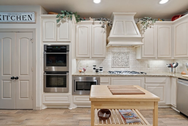 25672 Magnolia Pines Dr, Magnolia, TX 77355 - kitchen with appliances with stainless steel finishes, premium range hood, recessed lighting, backsplash, and light stone counters
