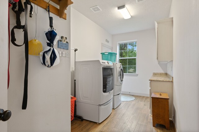 25672 Magnolia Pines Dr, Magnolia, TX 77355 - washroom with washing machine and clothes dryer, light wood finished floors, and cabinet space