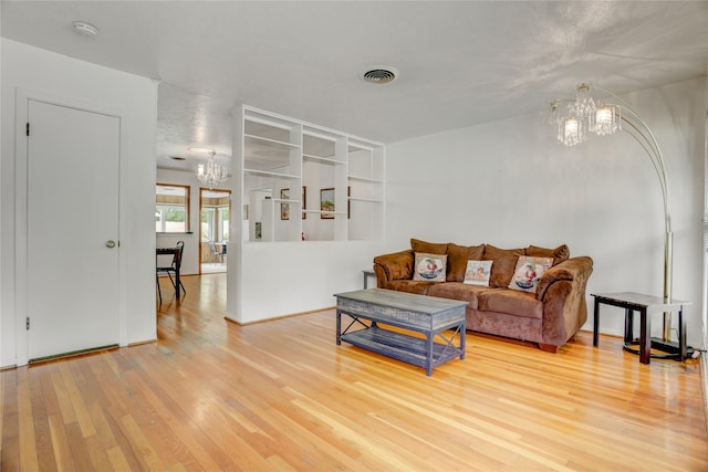 living area featuring visible vents, a chandelier, and light wood finished floors