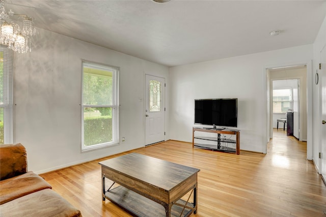 living area with light wood finished floors, a chandelier, and a healthy amount of sunlight