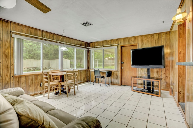 living room with light tile patterned flooring, a healthy amount of sunlight, and wood walls