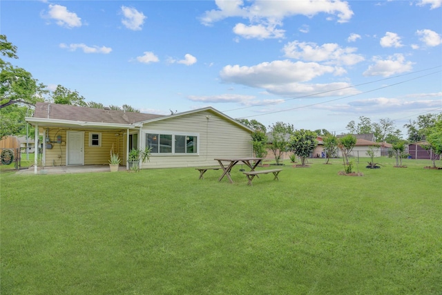 rear view of property featuring fence, a lawn, and a patio area