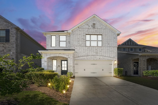 view of front of property featuring brick siding, an attached garage, and driveway
