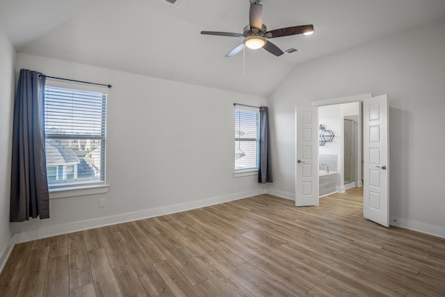 unfurnished bedroom featuring lofted ceiling, multiple windows, wood finished floors, and baseboards