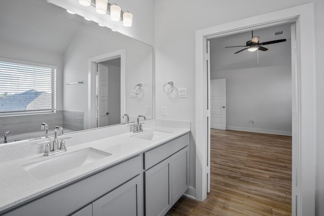 full bathroom featuring ceiling fan, wood finished floors, double vanity, and vaulted ceiling