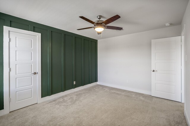 empty room featuring light carpet, ceiling fan, a smoke detector, and baseboards