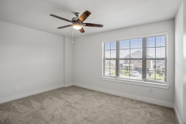 carpeted empty room with a ceiling fan and baseboards