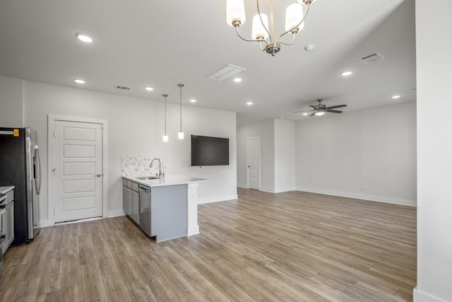 kitchen with a peninsula, a sink, stainless steel appliances, light countertops, and ceiling fan