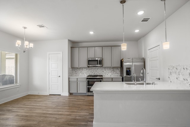 kitchen with appliances with stainless steel finishes, gray cabinets, a sink, decorative backsplash, and recessed lighting