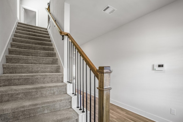 stairway with wood finished floors and baseboards