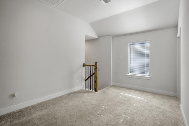 empty room with carpet floors, vaulted ceiling, and baseboards
