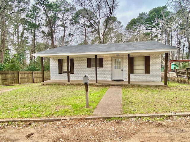 ranch-style home featuring fence, a front yard, covered porch, and brick siding