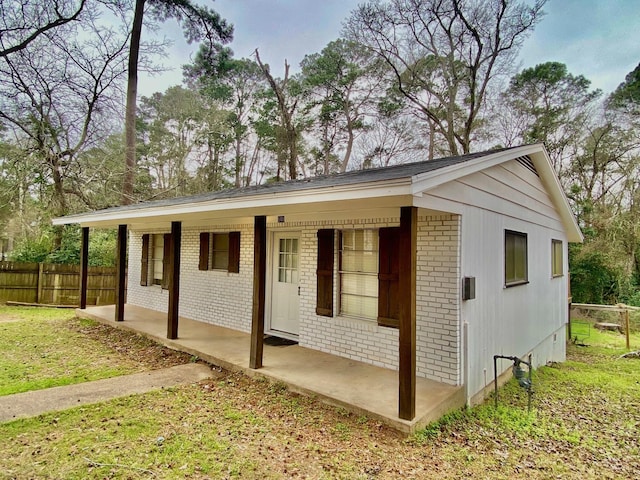 view of front of property with brick siding, a porch, a front lawn, and fence