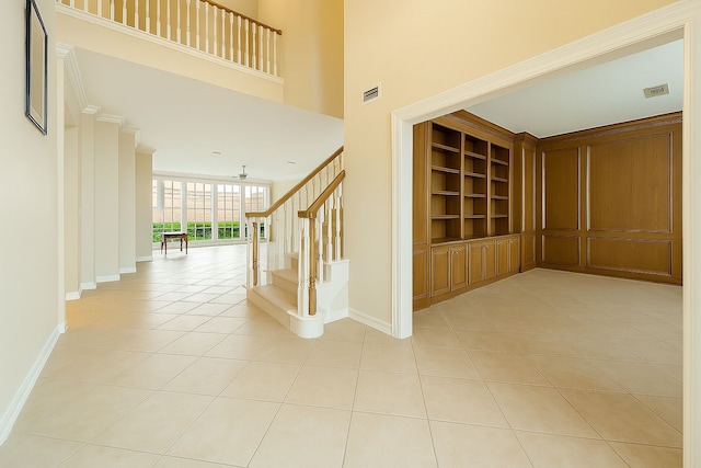 corridor featuring stairway, baseboards, light tile patterned flooring, and visible vents