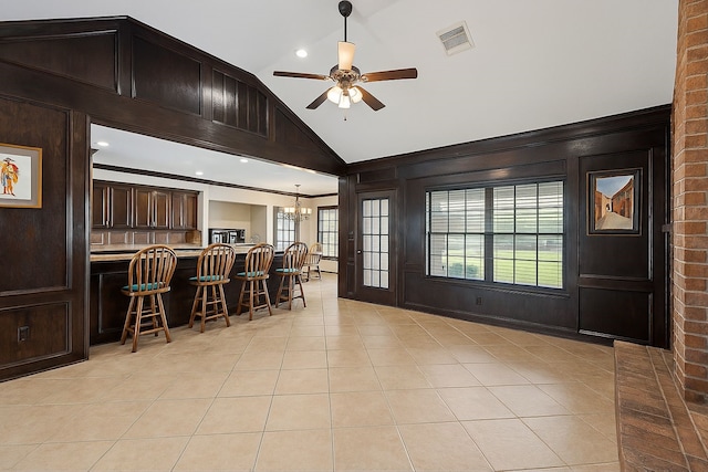 interior space with vaulted ceiling, crown molding, ceiling fan with notable chandelier, light tile patterned floors, and visible vents