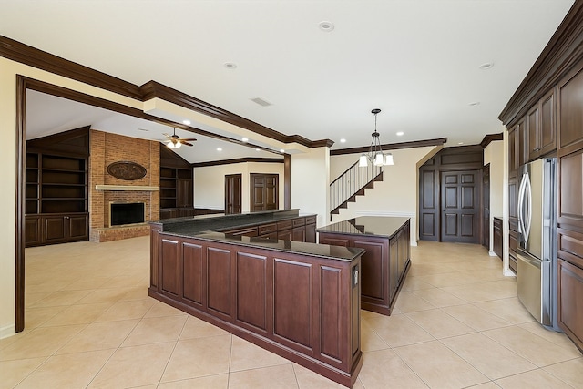 kitchen with dark countertops, ornamental molding, a kitchen island, and freestanding refrigerator