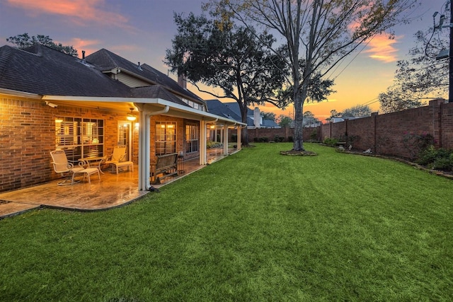 yard at dusk with a fenced backyard and a patio