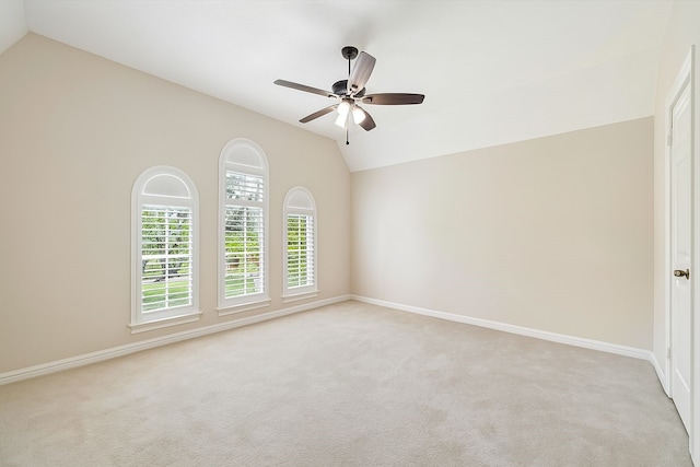spare room featuring light colored carpet, ceiling fan, lofted ceiling, and baseboards