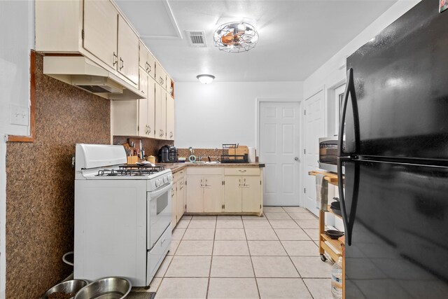 3721 Avalon Ave, Port Arthur, TX 77642 - kitchen featuring white gas range oven, visible vents, freestanding refrigerator, under cabinet range hood, and light tile patterned floors