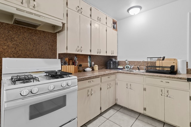 3721 Avalon Ave, Port Arthur, TX 77642 - kitchen with white range with gas cooktop, decorative backsplash, under cabinet range hood, and light tile patterned flooring