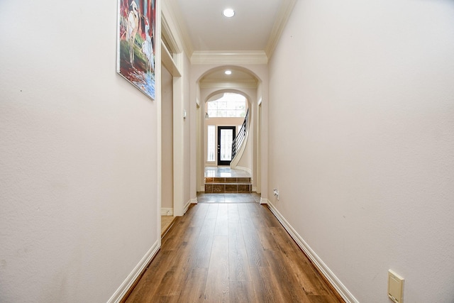 hall featuring crown molding, wood finished floors, arched walkways, baseboards, and recessed lighting