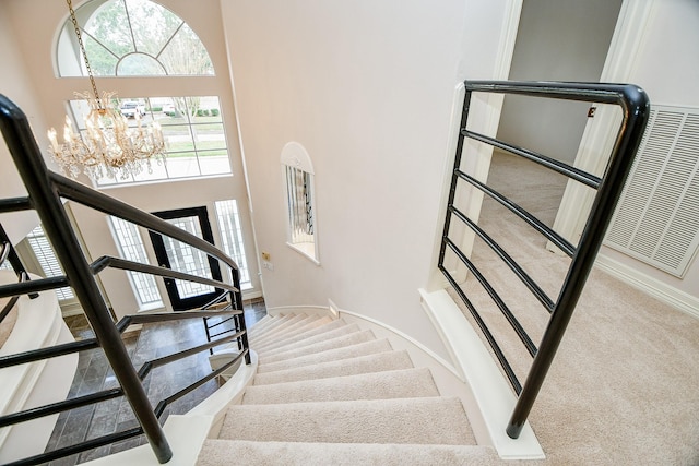 staircase featuring a chandelier, carpet floors, a high ceiling, and baseboards