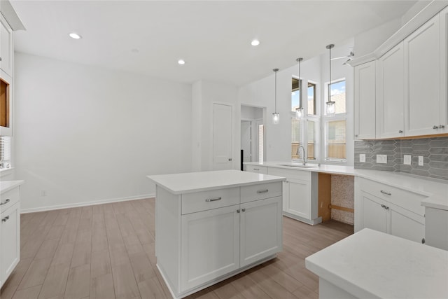 3220 Bello Green Ln, Katy, TX 77493 - kitchen with a sink, light wood-type flooring, tasteful backsplash, a kitchen island, and white cabinets