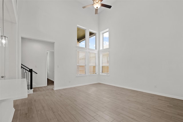 3220 Bello Green Ln, Katy, TX 77493 - unfurnished room featuring a towering ceiling, ceiling fan, light wood-style floors, baseboards, and stairs