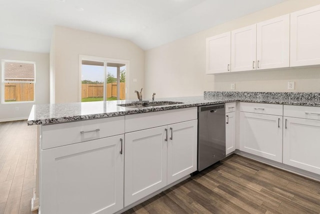 kitchen with white cabinets, dark wood finished floors, stainless steel dishwasher, a sink, and a peninsula