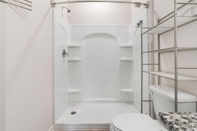 bathroom featuring toilet and a stall shower
