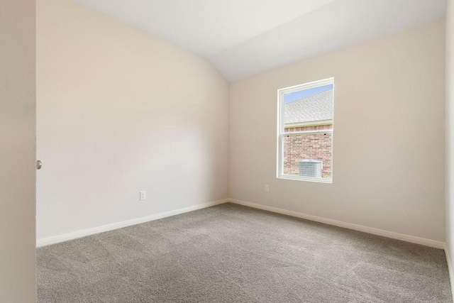 carpeted empty room featuring vaulted ceiling and baseboards